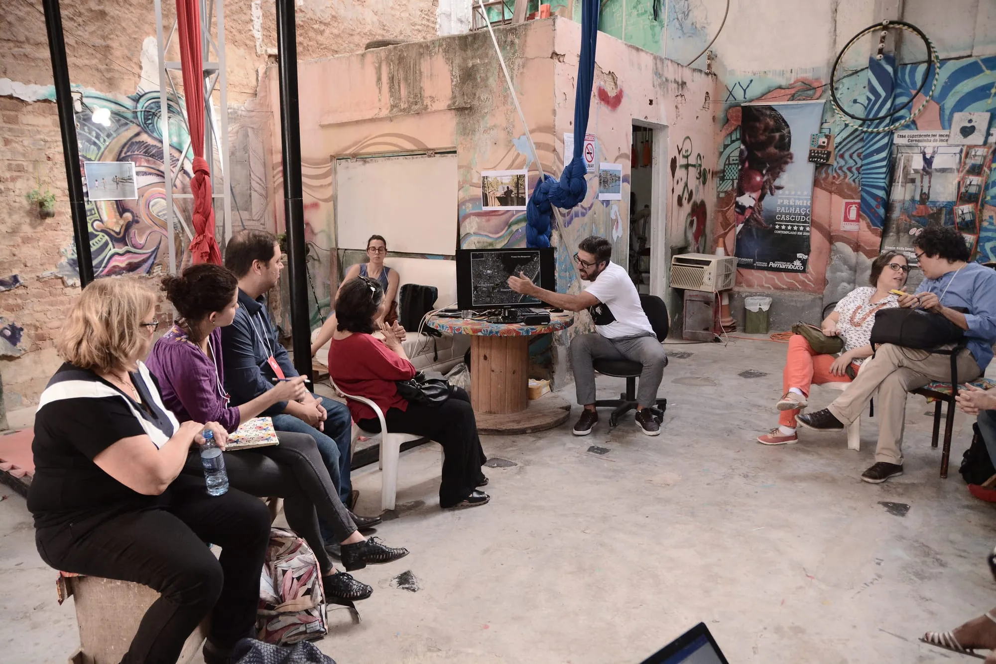 A round-table discussion in an open courtyard with participants seated around a speaker