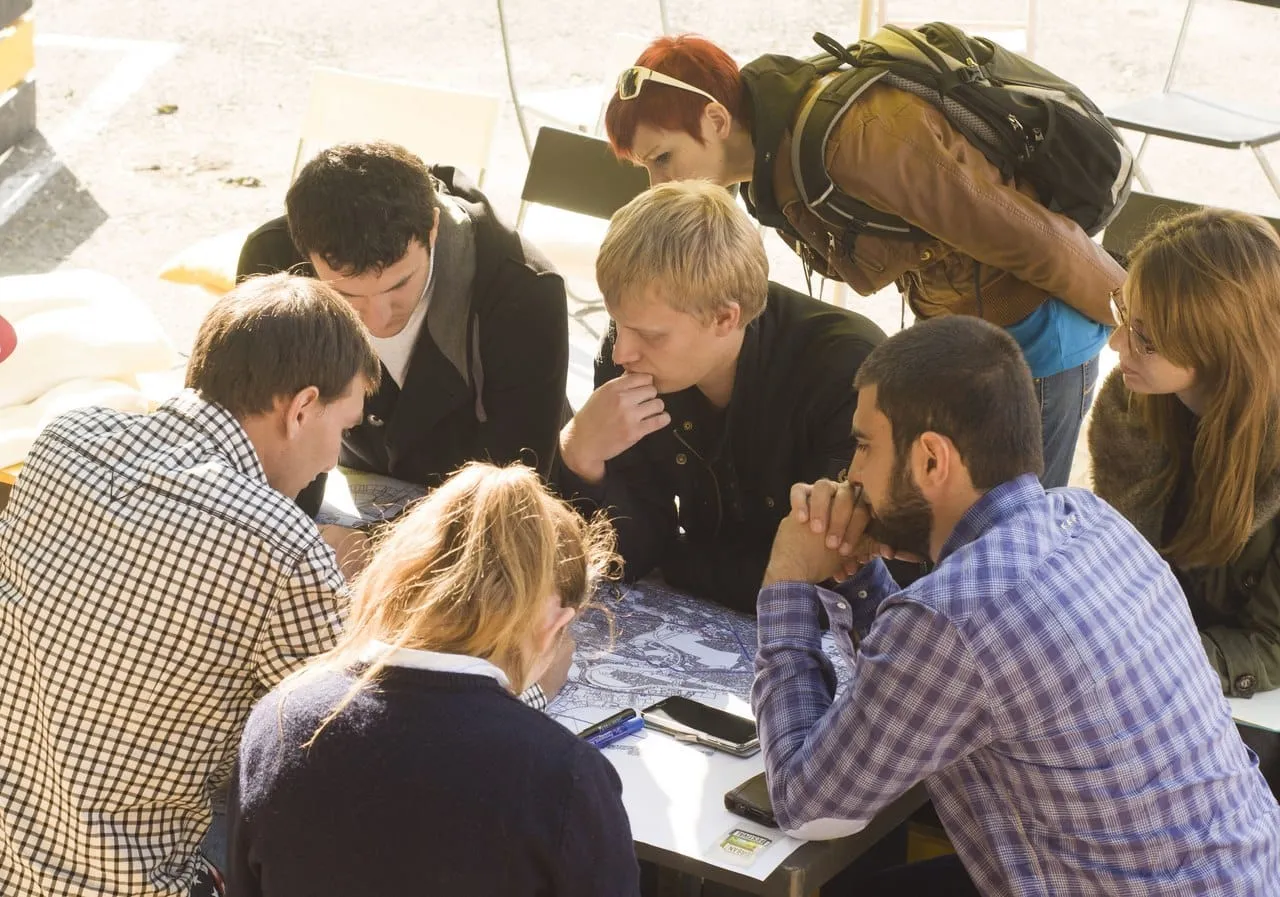 Participants of a cycling workshop discussing routes over a city map