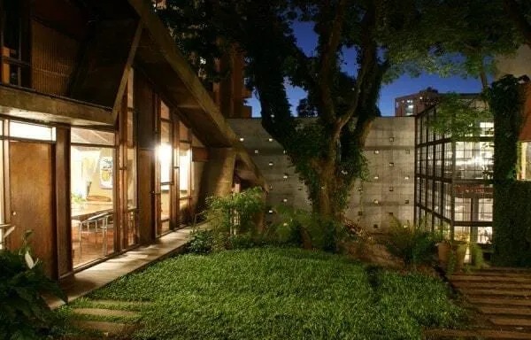 The green courtyard of Jaime Lerner's studio in Curitiba at night, with lit glass-walled buildings among trees