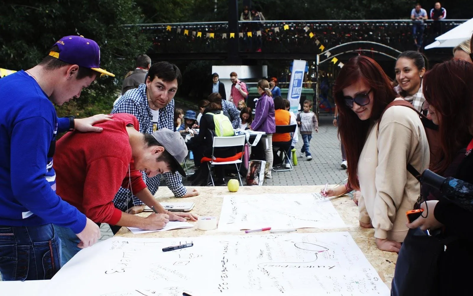 Young people leaning over a large paper map, drawing and writing ideas for the city