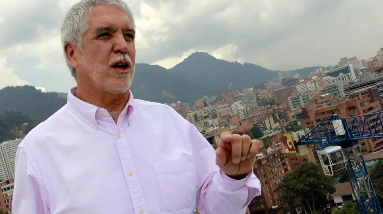 Enrique Peñalosa talking on a rooftop, with Bogotá and the green mountains behind him