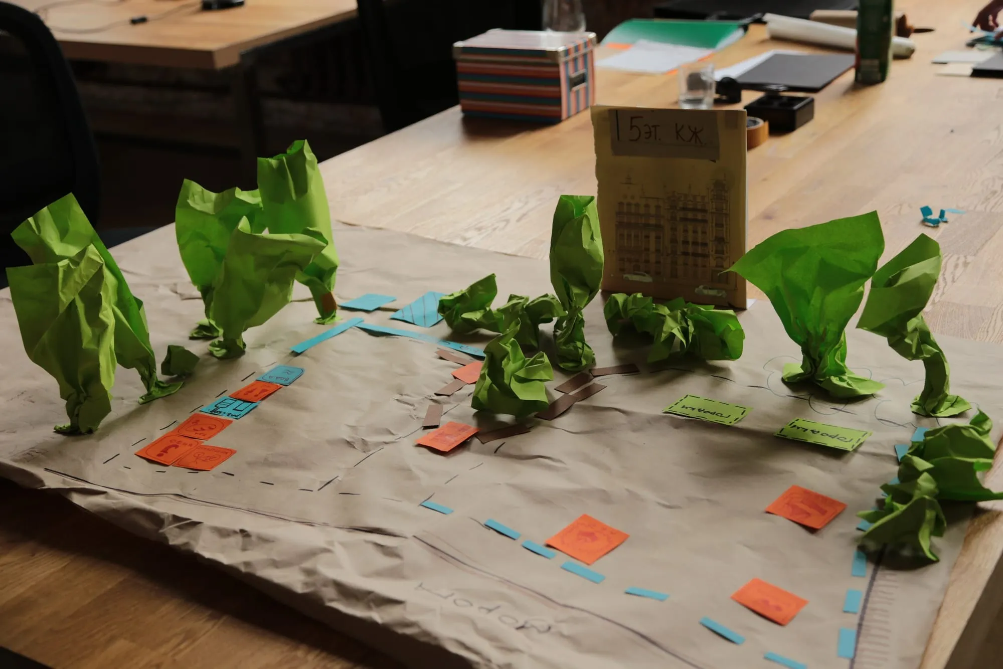 A workshop model of a public space with paper trees and coloured markers on kraft paper