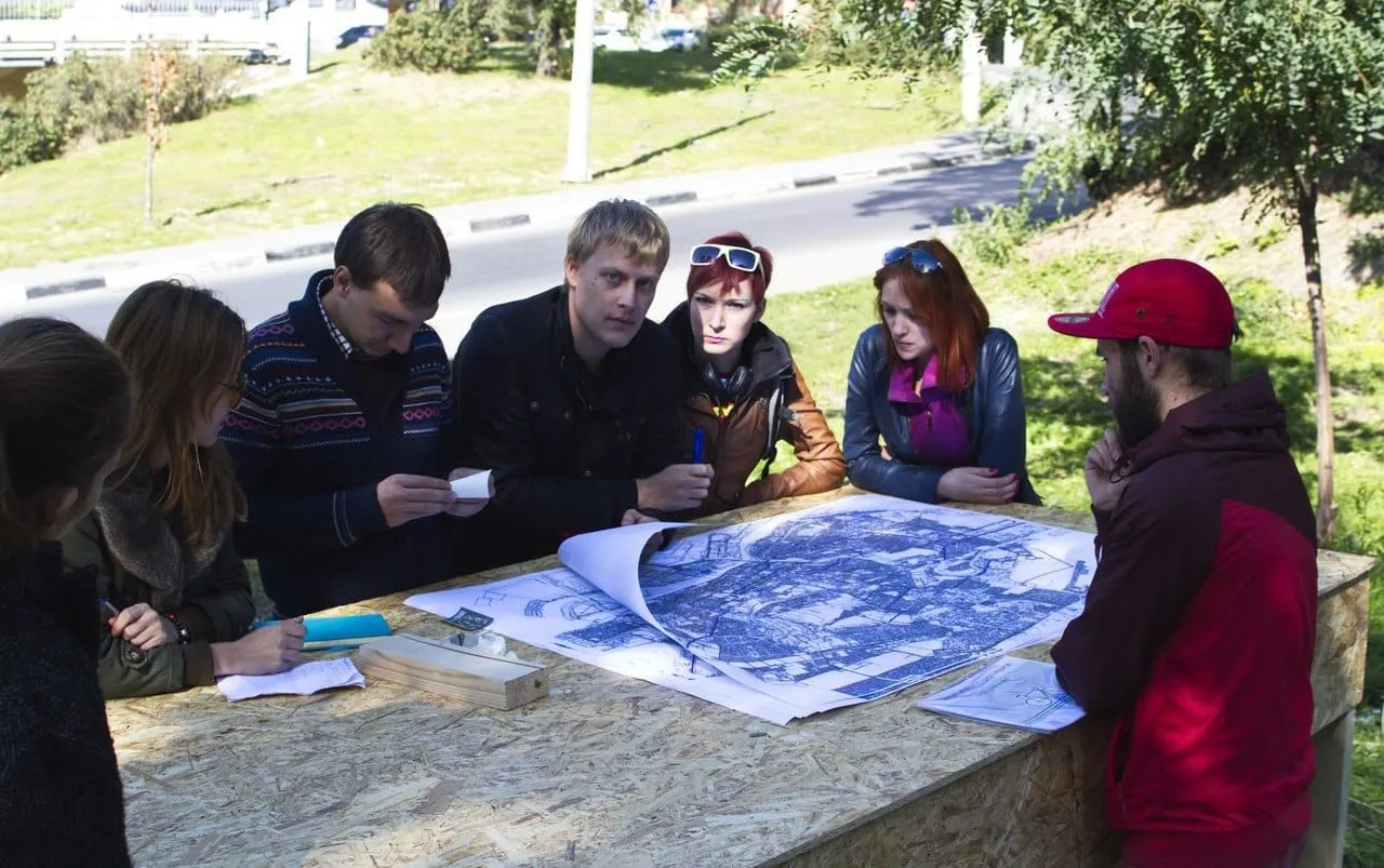 Participants studying a city plan spread out on a wooden table outdoors