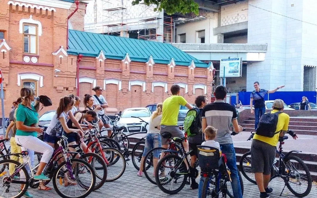 A group bike ride on a cobbled street past an old red-brick building in Rostov-on-Don