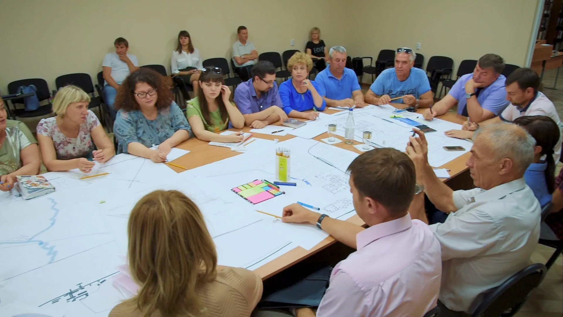 Residents and the project team working over large plans of the town at a public workshop